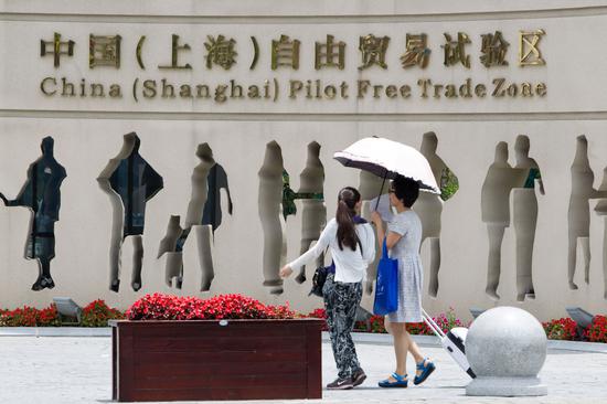 Pedestrians walk past the entrance of the China (Shanghai) Pilot Free Trade Zone. (Photo by Wu Jun/For China Daily)
